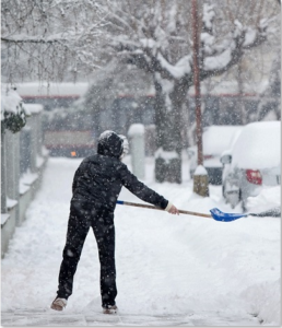 Man Shovels winter sidewalk covered in snow